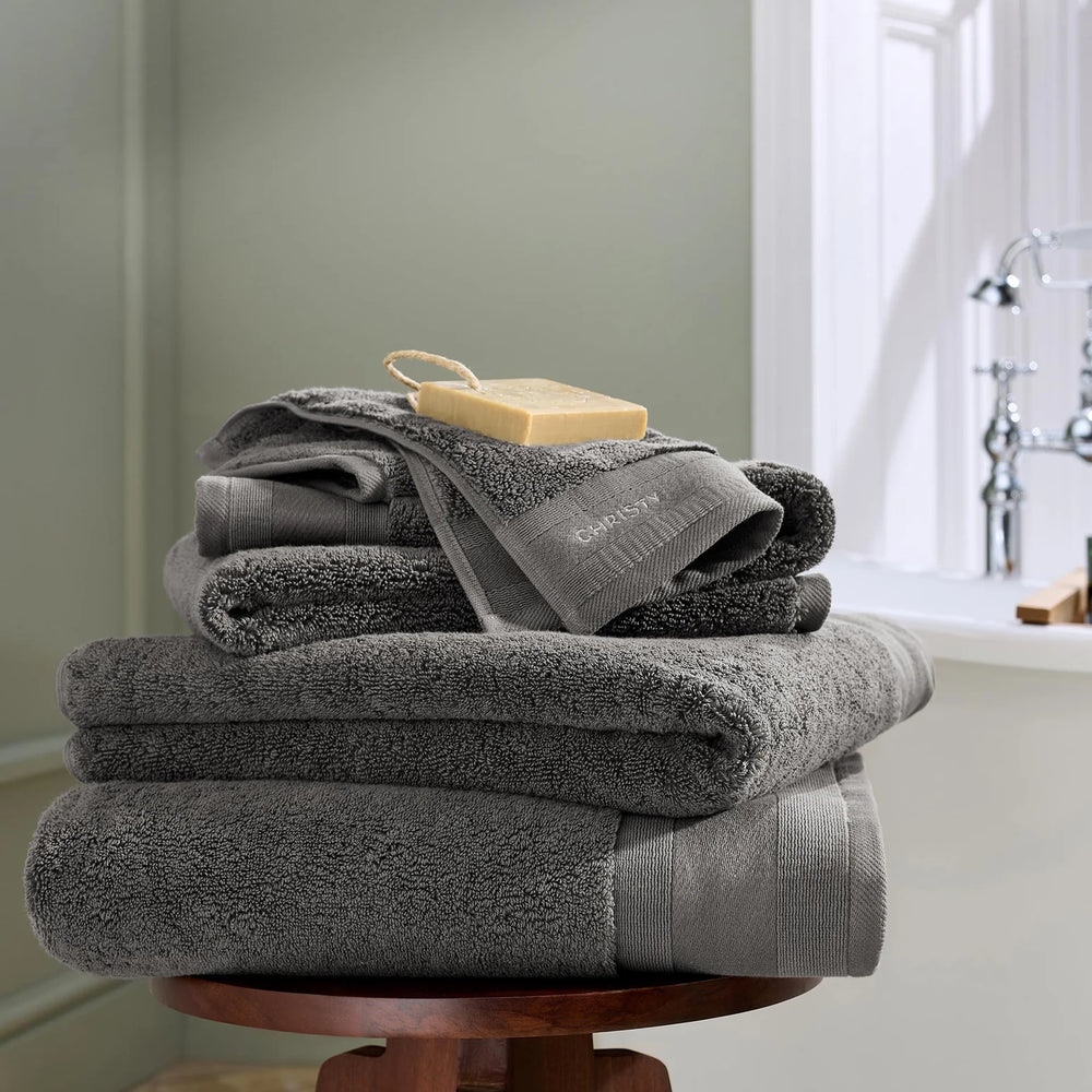 Stack of gray towels on a wooden stand with a blurred bathroom background
