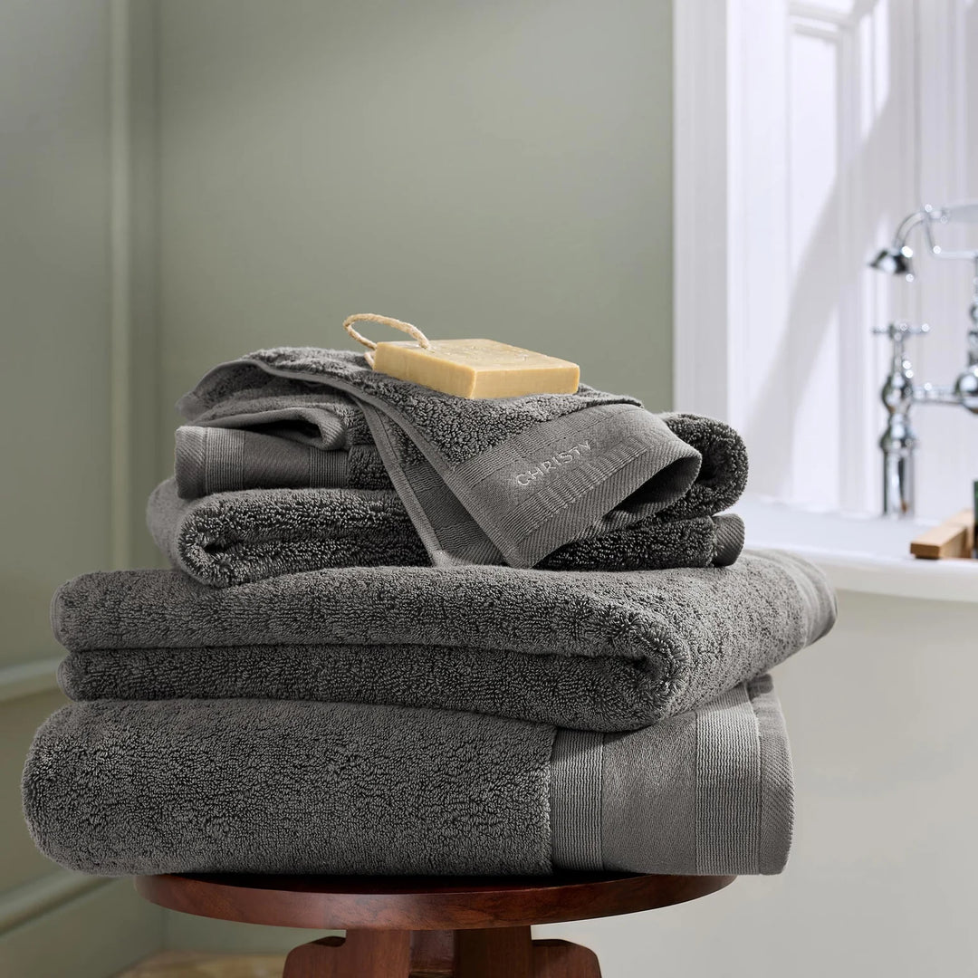 Stack of gray towels on a wooden stand with a blurred bathroom background