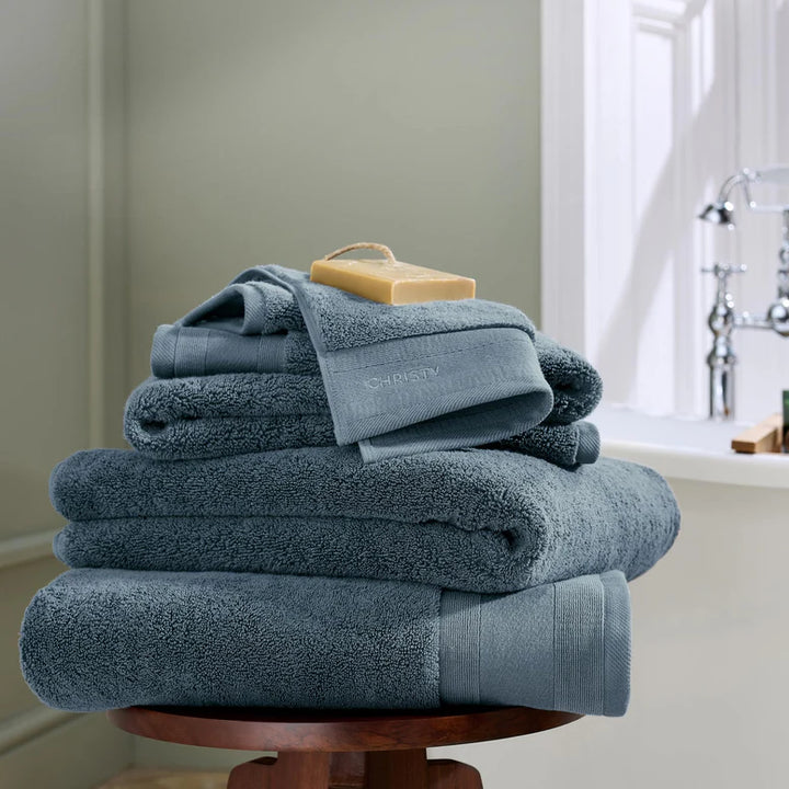 Stack of blue towels on a wooden stool in a bathroom setting