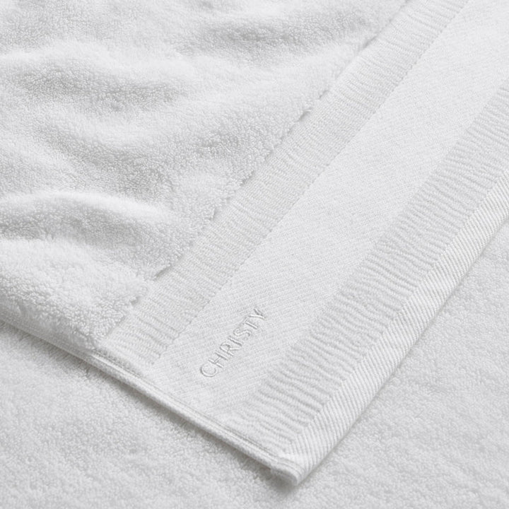 Close-up of a white towel with a brand logo on a light gray background
