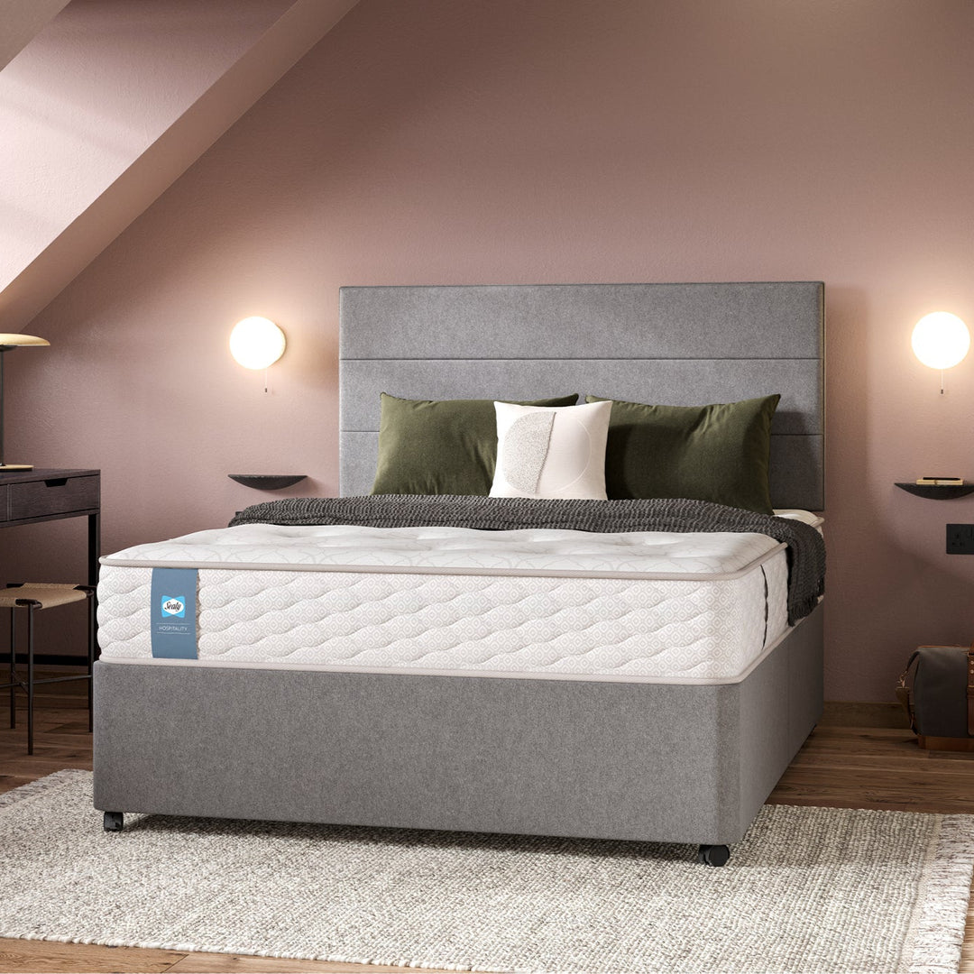 Grey upholstered divan with a Sealy Tudor contract mattress in a hotel bedroom setting