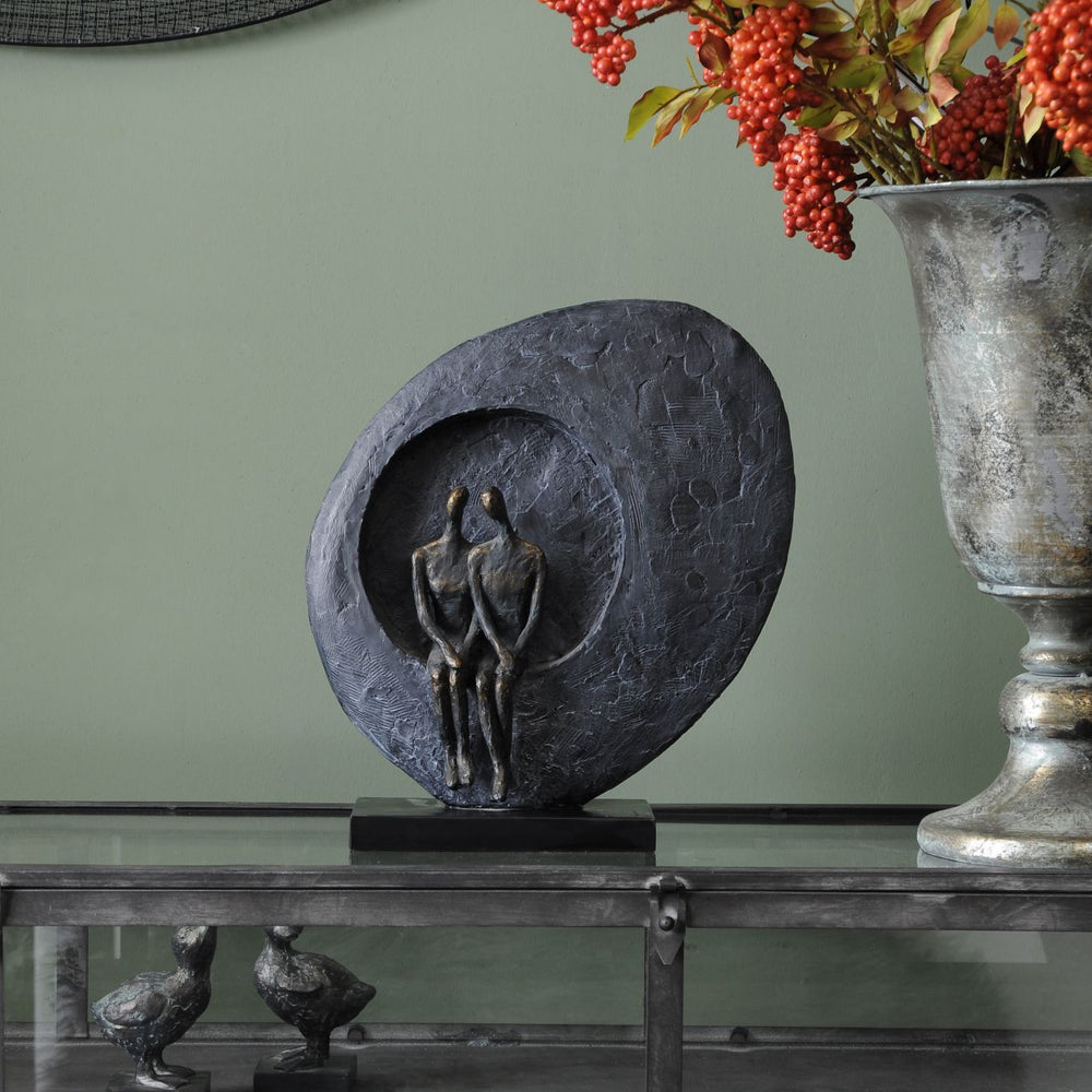 Decorative sculpture of a woman in a circular frame on a table with a vase of red berries in the background.