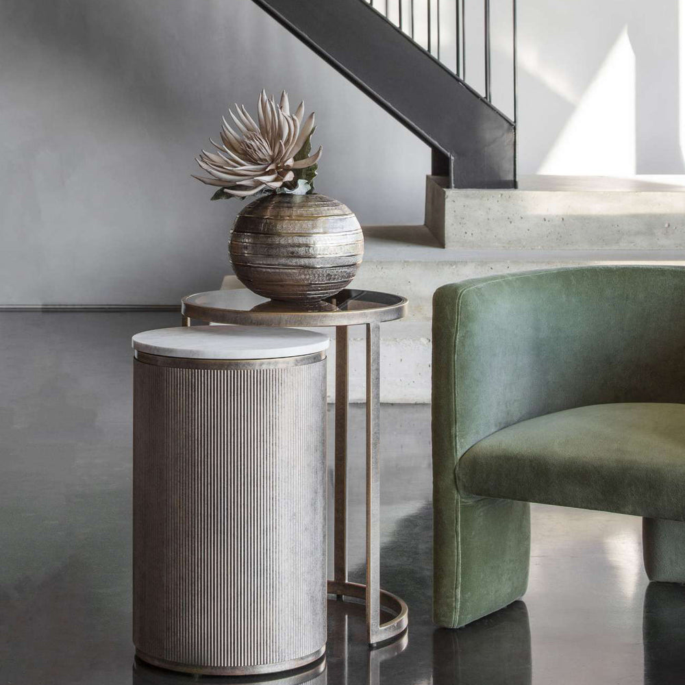Decorative side table with a textured vase and plant in a modern interior setting.