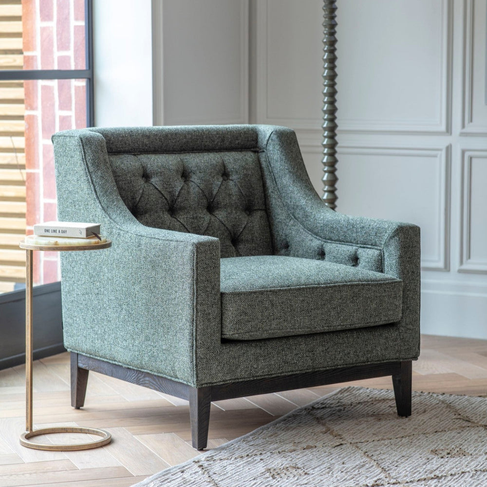 Forest green upholstered armchair in a living room setting with a side table and lamp.