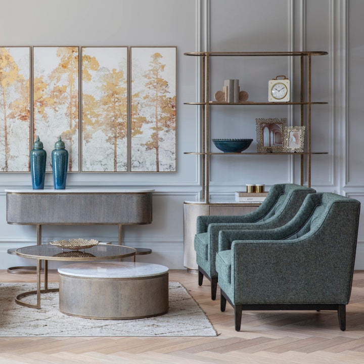 Modern living room with Forest green armchairs, round coffee table, and decorative wall art.