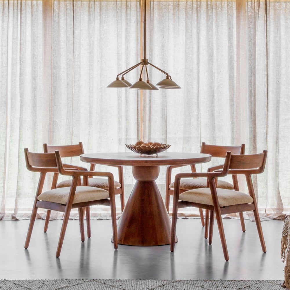 Dining room with wooden table and chairs under a chandelier, large windows in the background.