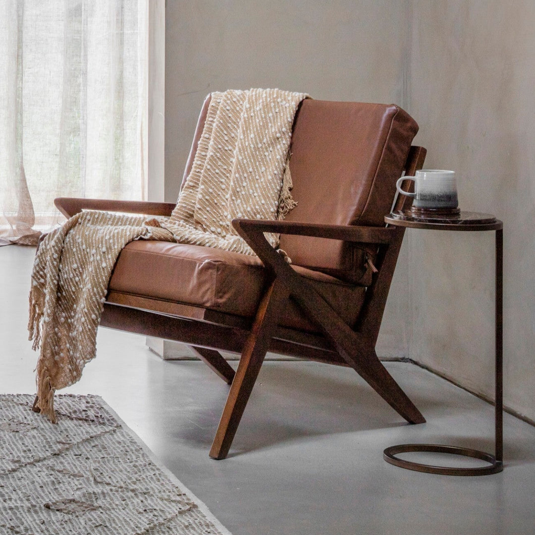 Brown leather armchair with a blanket in a minimalistic room.