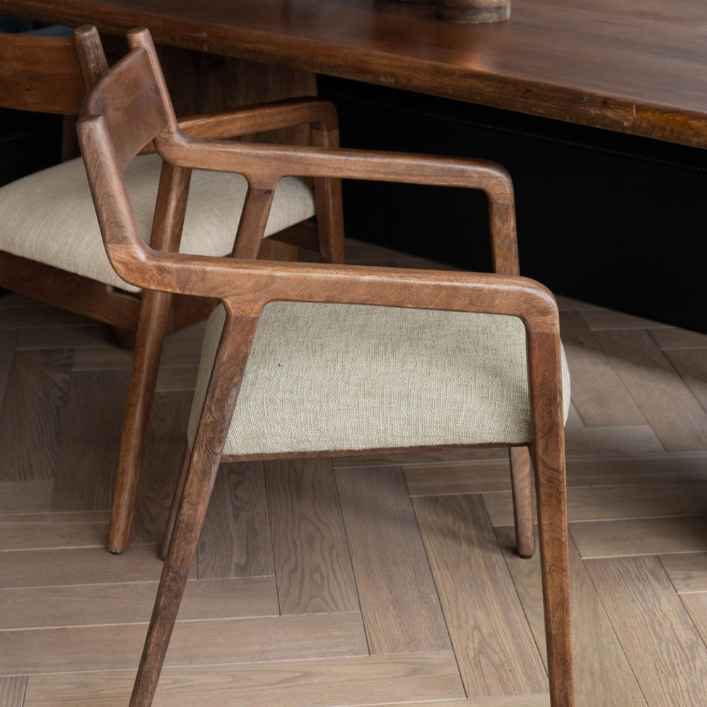 Wooden chair with a cushioned seat in front of a wooden table.