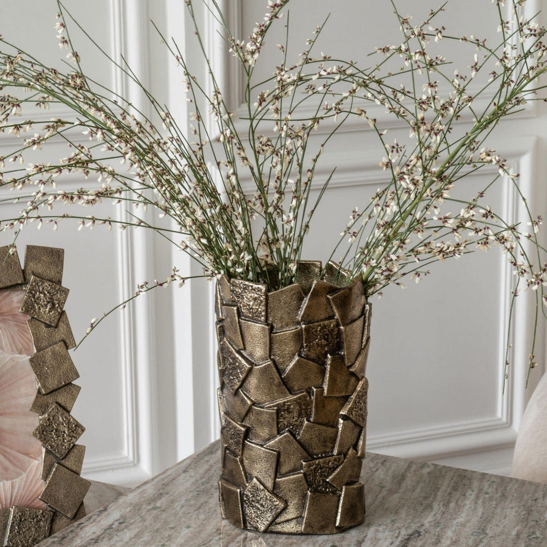 Bronze textured vase with dried plants on a marble table