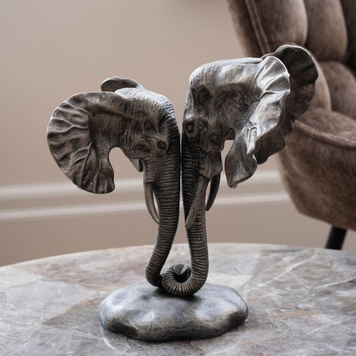 Bronze elephant sculpture on a marble surface with a blurred chair in the background