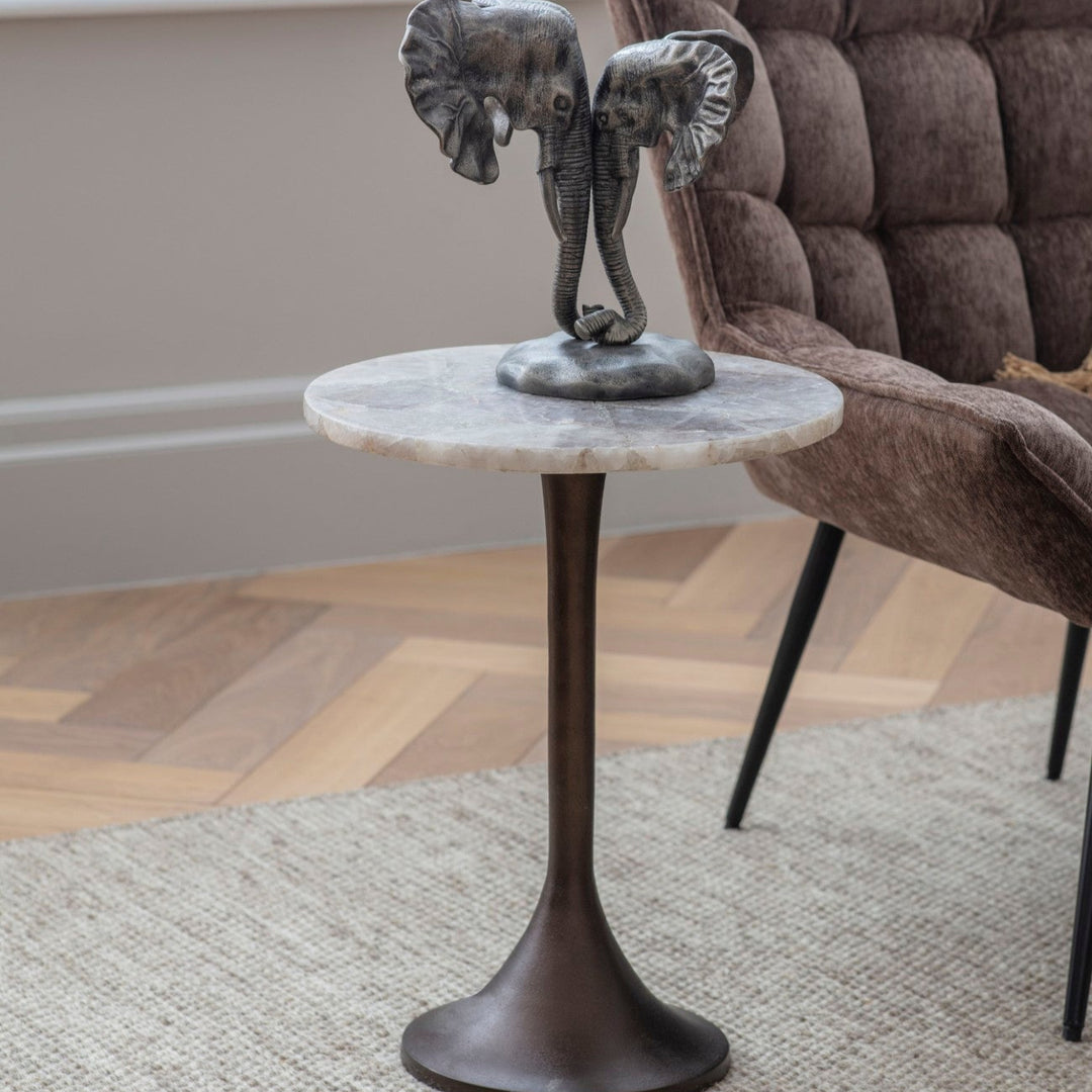 Small round marble table with elephant sculpture in a living room setting