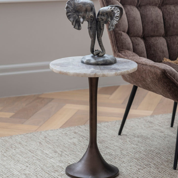 Small round marble table with elephant sculpture in a living room setting
