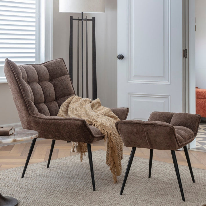 Brown upholstered chairs with a blanket in a room with a lamp and door.