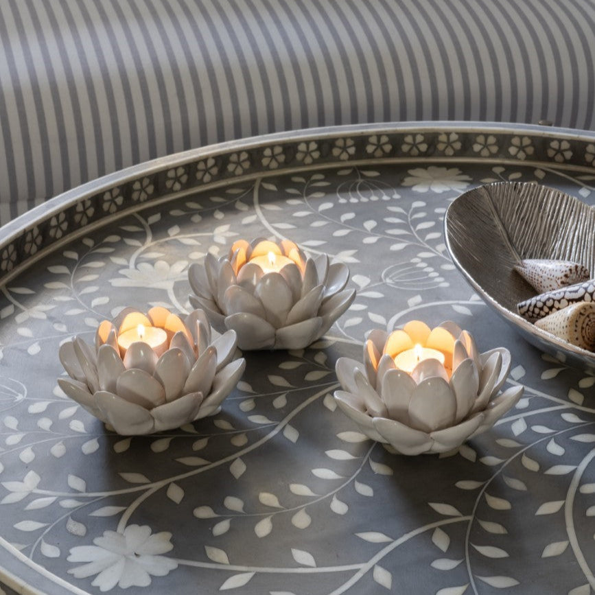 Decorative candles on a patterned coffee table with pillows in the background