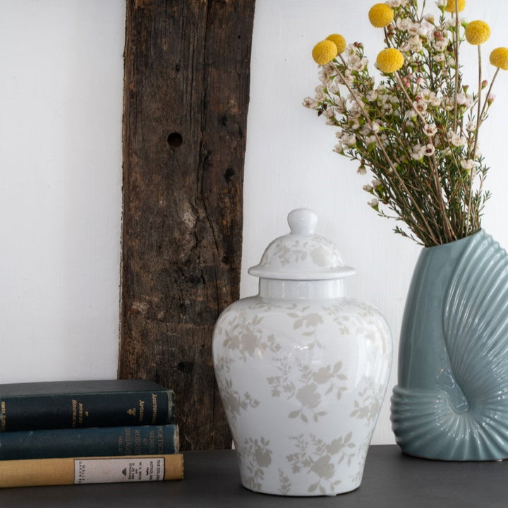 Decorative items including a white vase, blue vase, and books on a wooden surface.