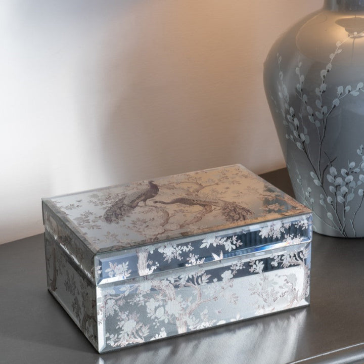 Decorative box with floral patterns on a surface next to a lamp.