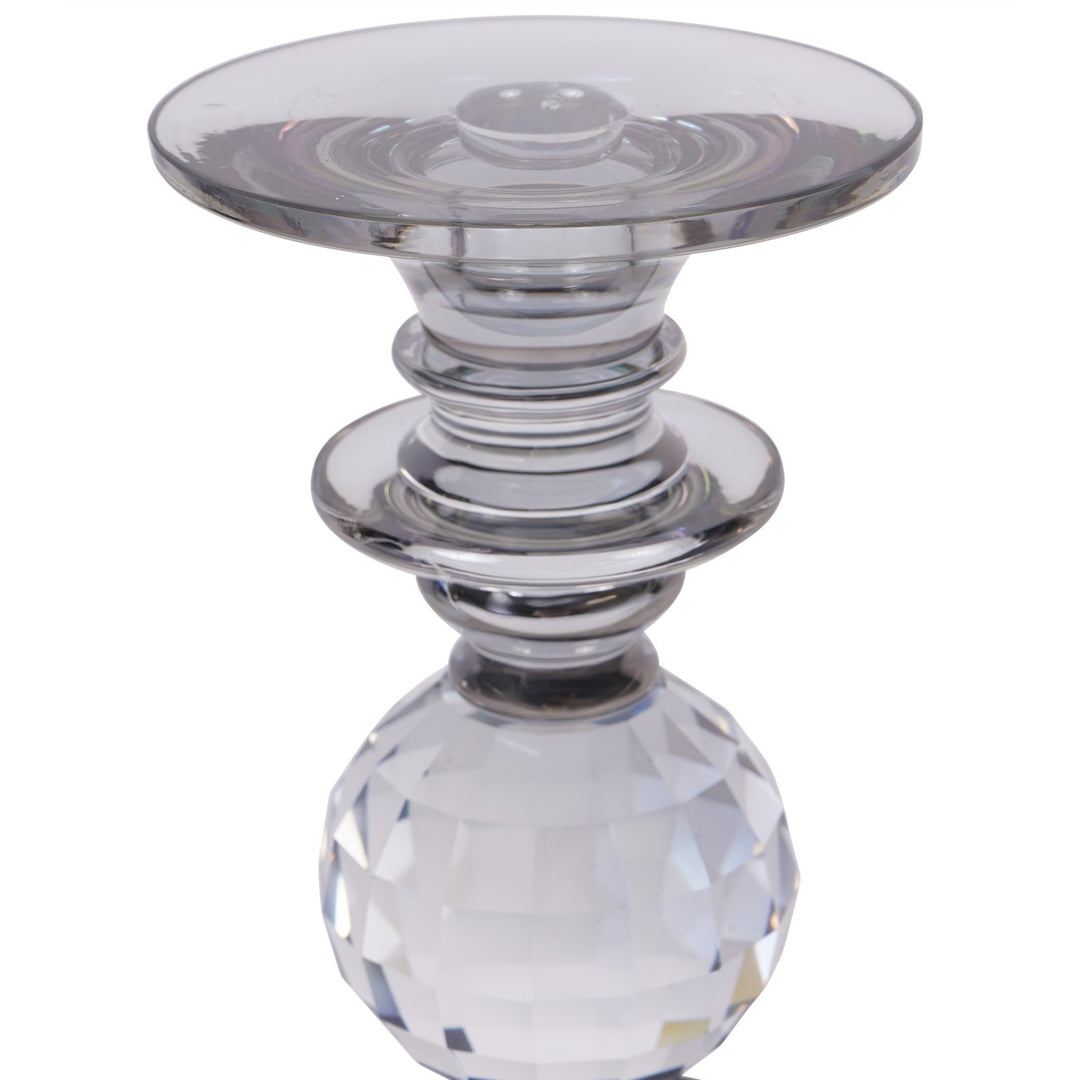 Clear glass candle holder with a faceted base on a white background