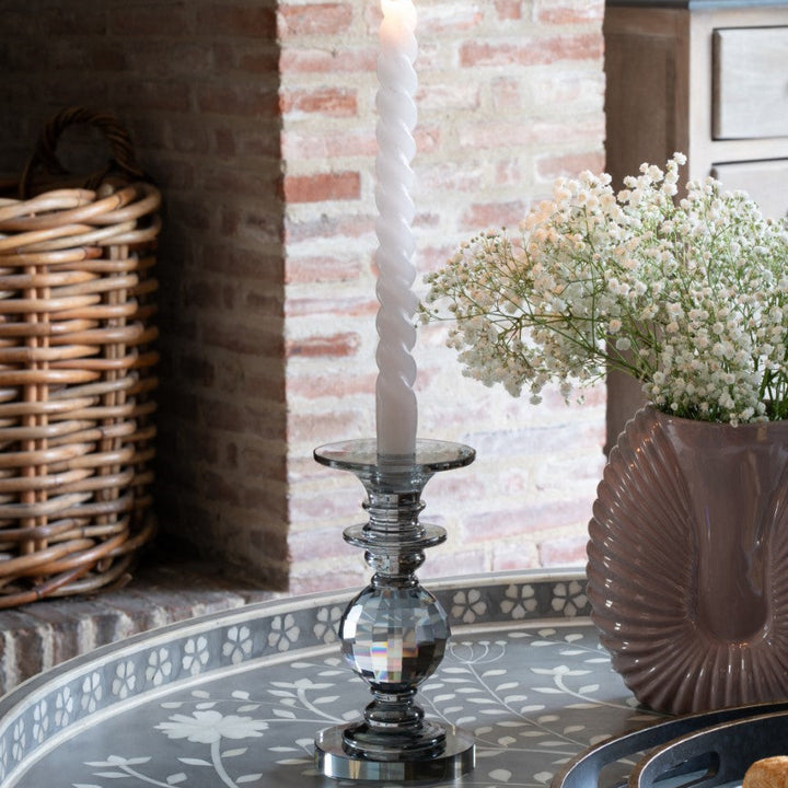 Candle in a metallic holder on a decorative table with a brick wall background