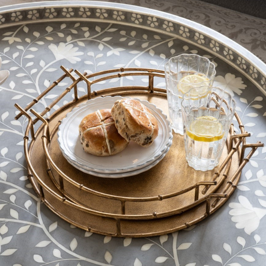 Round wooden tray with pastries and lemon slices on a patterned table