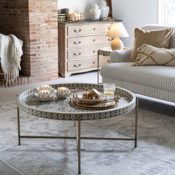 Living room with round coffee table, sofa, and fireplace.