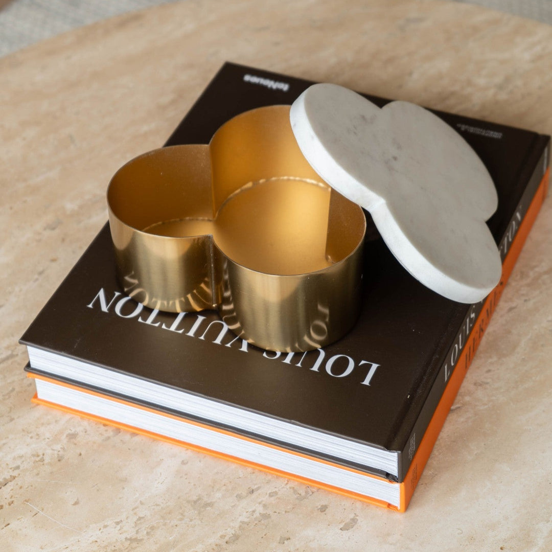 Decorative box with marbled top and gold cylindrical base on a coffee table