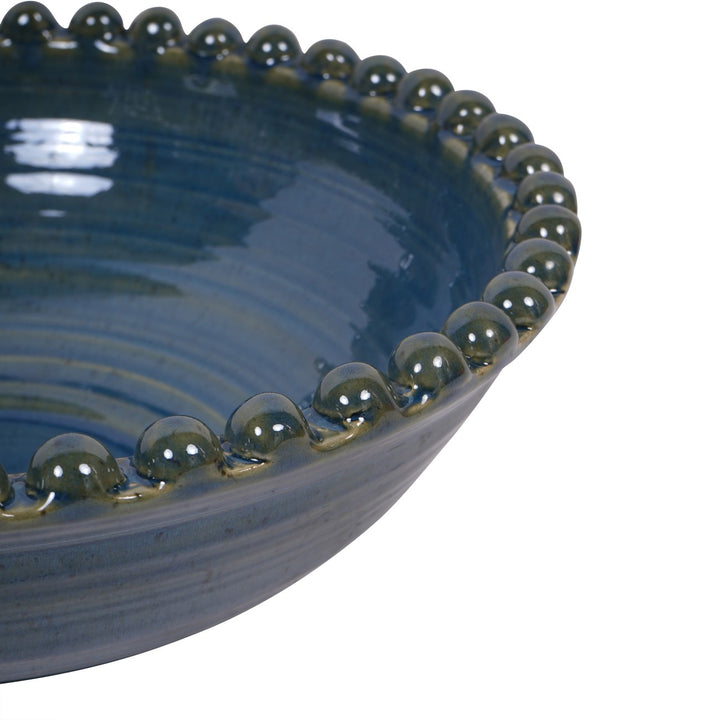 Close-up of a blue ceramic bowl with decorative edge on a white background