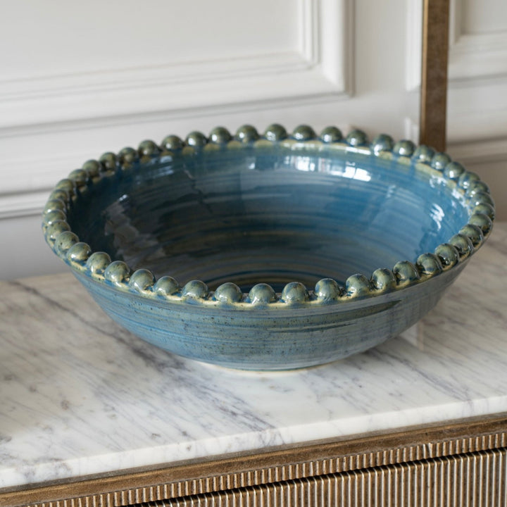 Blue ceramic bowl with decorative edge on a marble surface