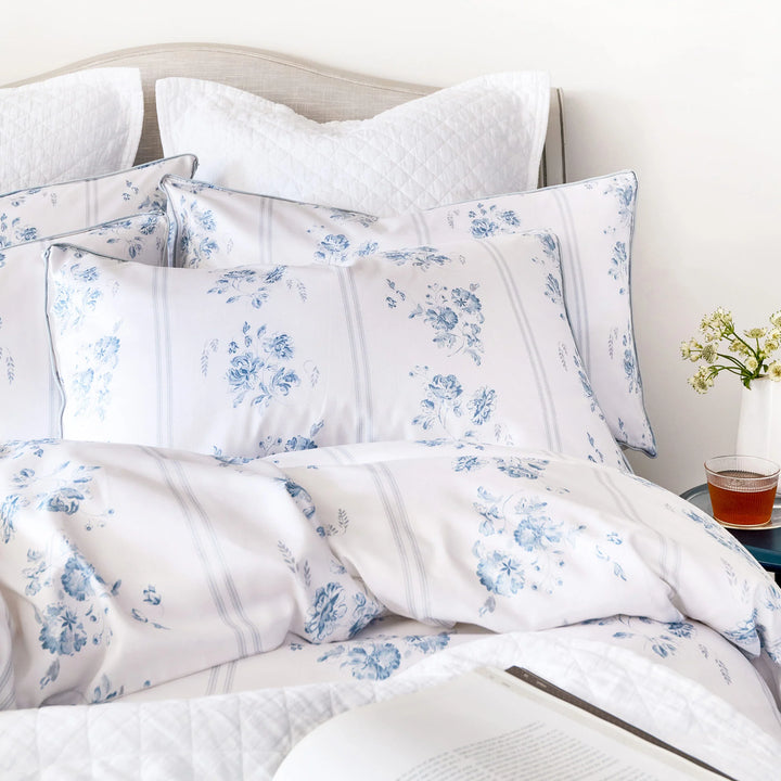 Floral patterned bedding set on a bed with a side table in the background.