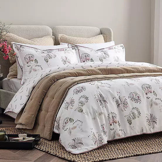 Bedroom with floral bedding and beige pillows on a bed.