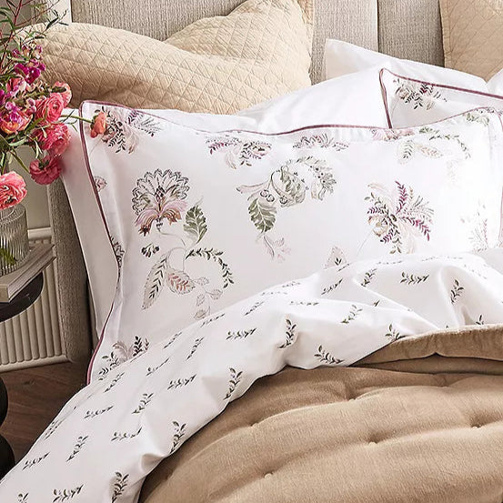 Floral patterned bedding set on a bed with pillows and a quilt.