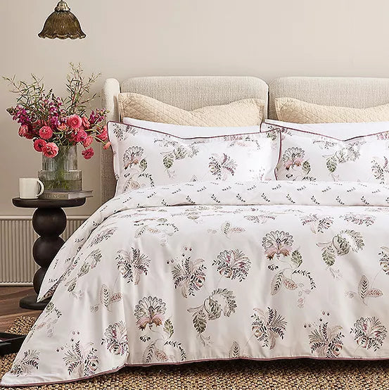 Floral patterned bedding set on a bed with a side table and flowers in the background.