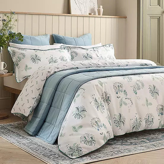 Bedroom with floral bedding set on a bed, side table, and wall art.