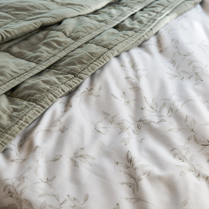 Green quilted cover on a floral-patterned bedspread