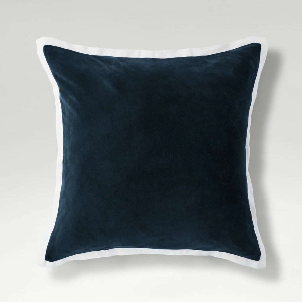 Navy blue pillow with white trim on a light gray background