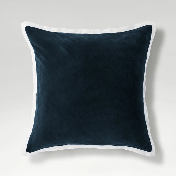 Navy blue pillow with white trim on a light gray background