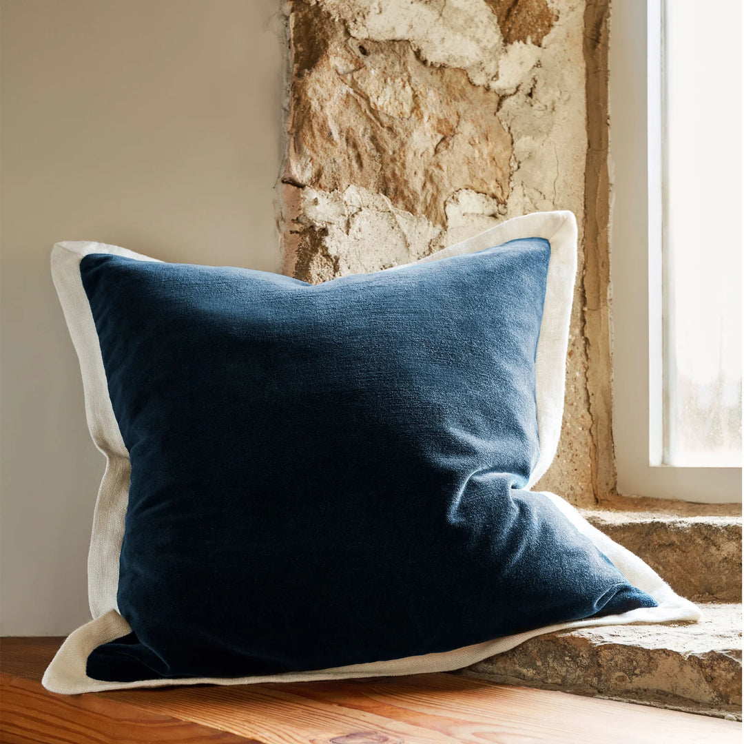 Blue pillow on a wooden surface with a stone wall background