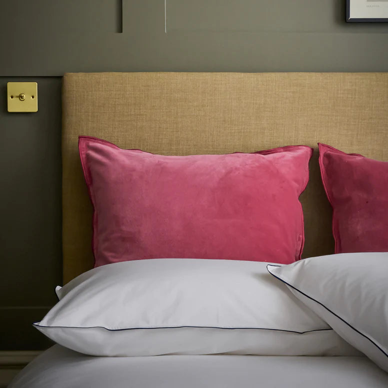 Bed with pink and white pillows against a beige headboard.