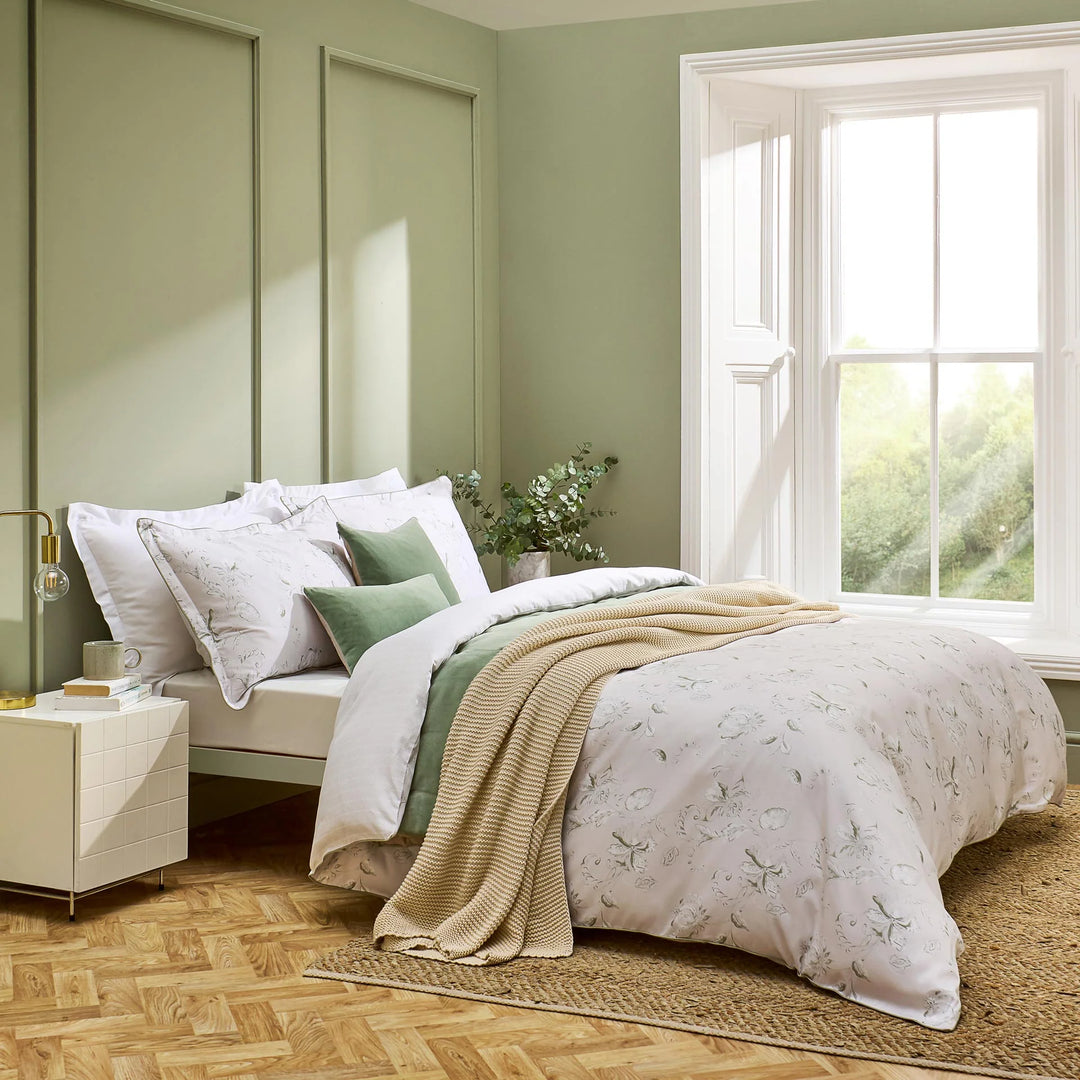 Neatly made bed with white bedding and green accents in a bright bedroom.