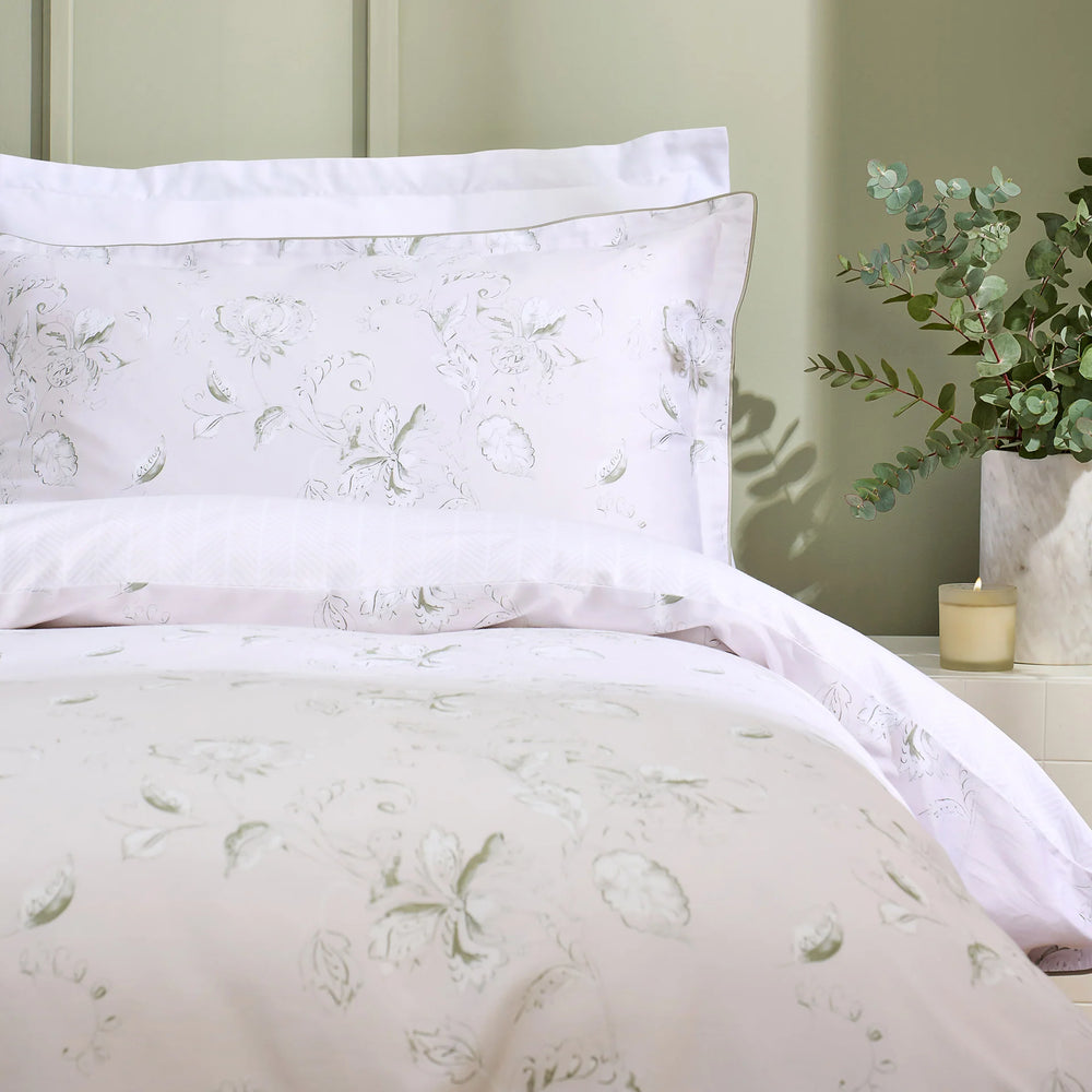 Floral patterned bedding set on a bed with a green wall and plant in the background