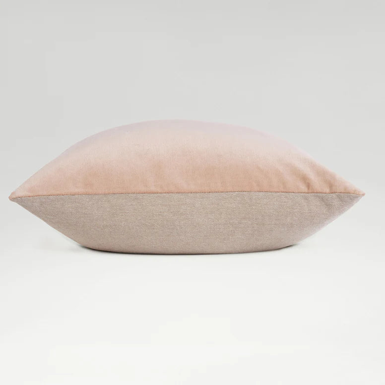 Two-toned pink and beige pillow on a light gray background
