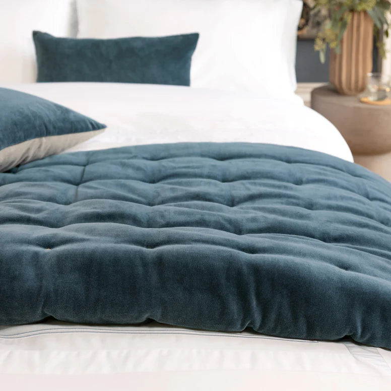 Teal comforter on a bed with white pillows in a bedroom setting