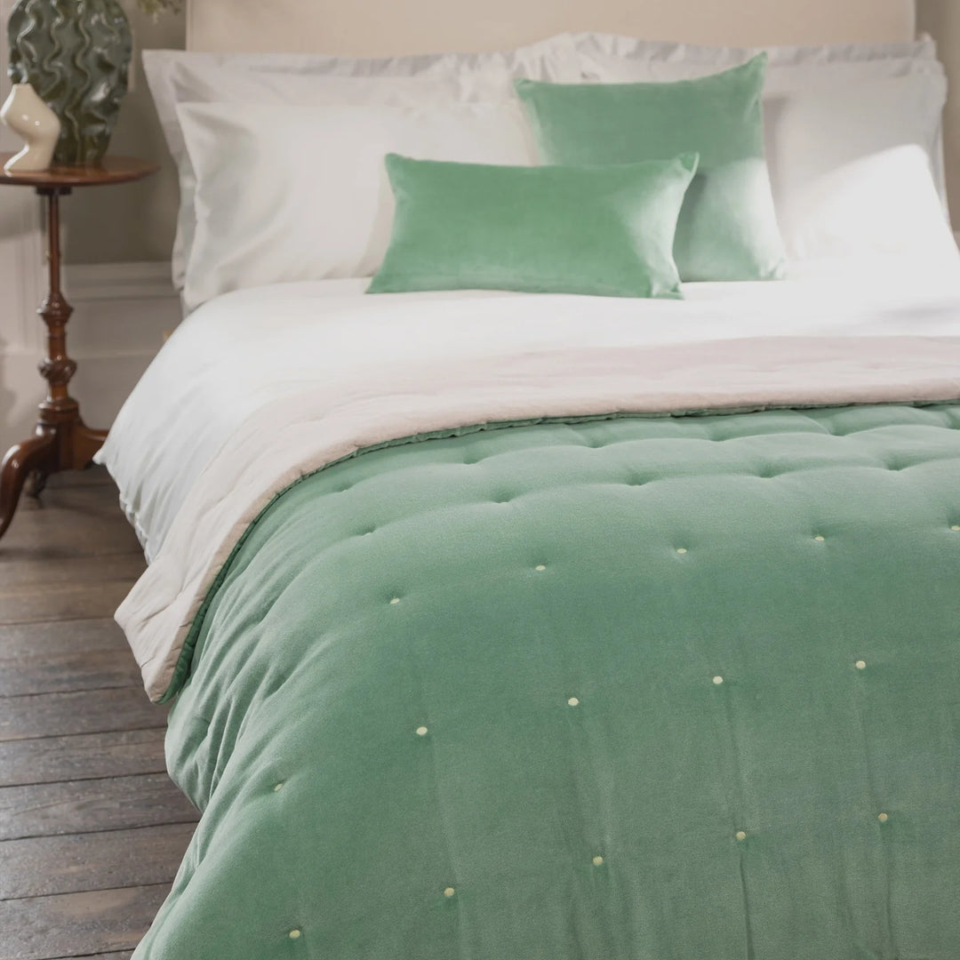 Bed with green and white bedding in a bedroom setting