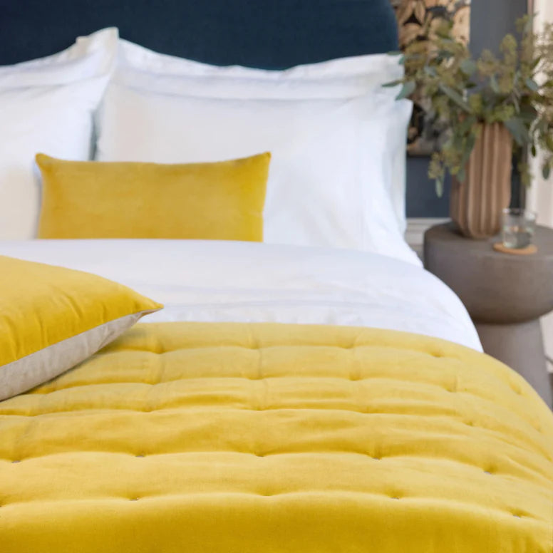 Yellow bedding set on a bed with white pillows in a bedroom setting.