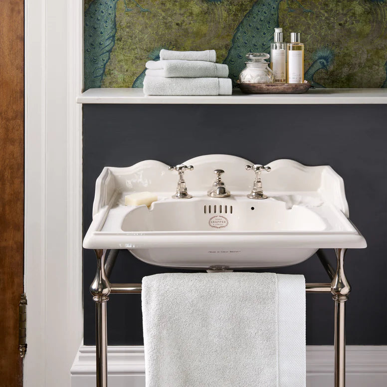 Vintage-style white sink with silver faucet and CHRISTY Luxe - French Grey against a dark wall.