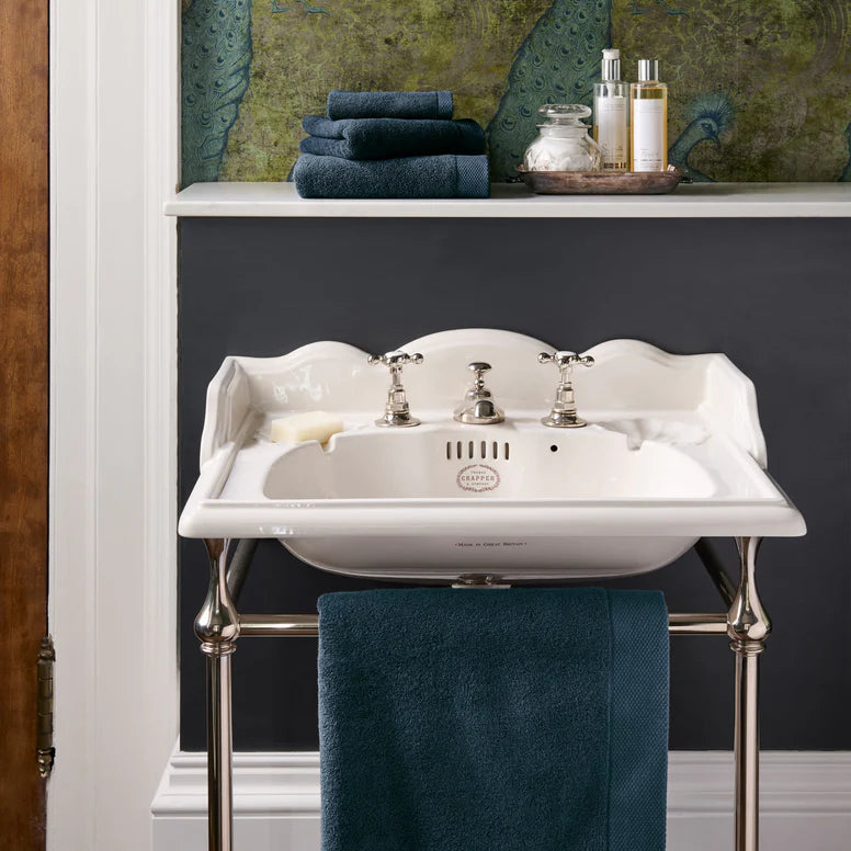 White sink with blue towels and toiletries in a bathroom setting