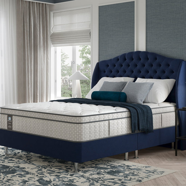 Blue upholstered bed in a hotel bedroom with a Sealy Regal mattress