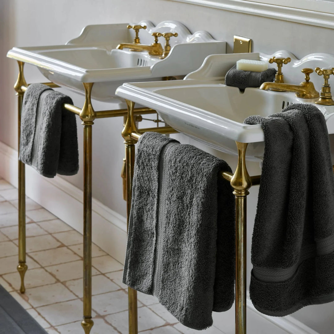Bathroom vanity with white sinks, gold fixtures, and CHRISTY Renaissance Towels - Ash Grey