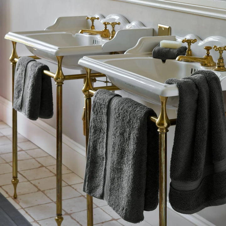 Bathroom vanity with white sinks, gold fixtures, and CHRISTY Renaissance Towels - Ash Grey