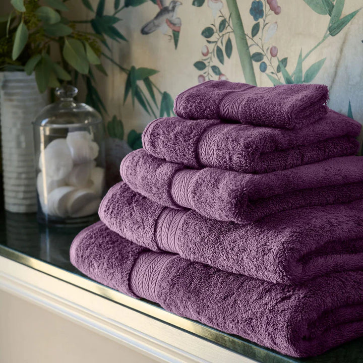 Stack of CHRISTY Renaissance Towels - Berry on a surface with decorative background