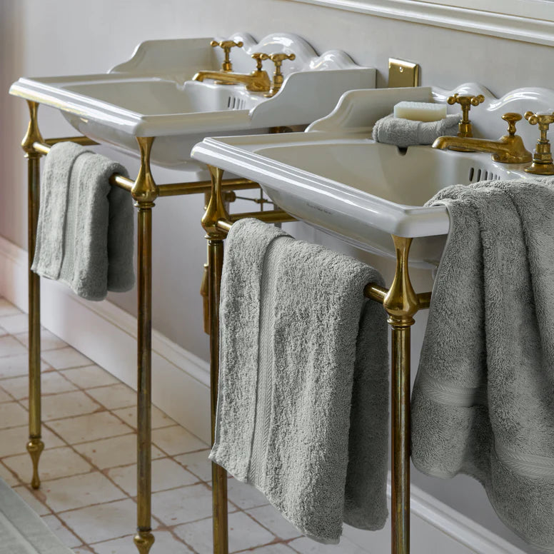 Bathroom vanity with white sinks, gold fixtures, and CHRISTY Renaissance Towels - Dove Grey.